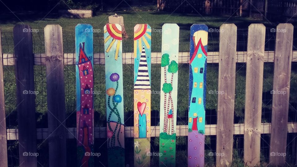 Picket Fence Art. Riding along a street and came across this wonderful and colorful art on a picket fence. It gives the fence more character and shows imagination.