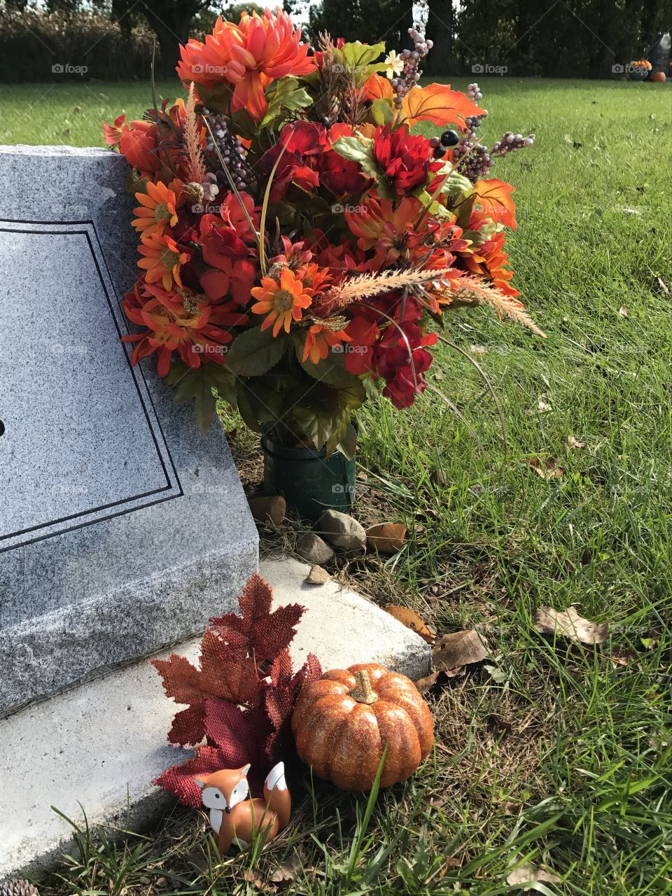 Monument at a grave decorated for fall