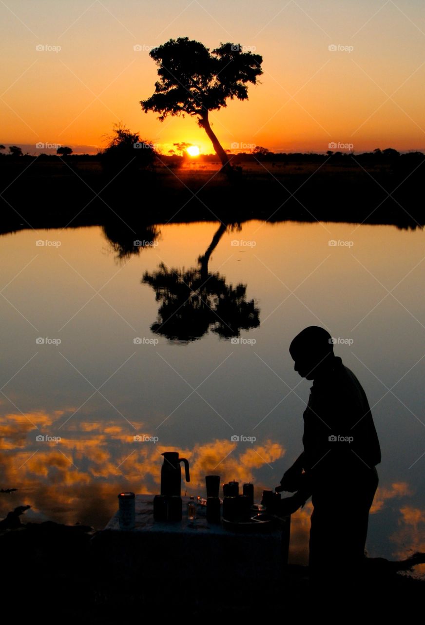Sundowner in Botswana. Our guide sets up snacks and drinks while the sun sets on safari in Botwana. This is known as a 'sundowner'.