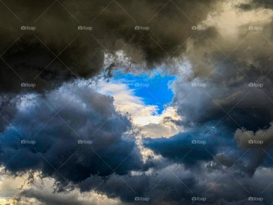 White clouds in the sky.  And dark clouds.  The sky is blue.  It is a very beautiful picture.
