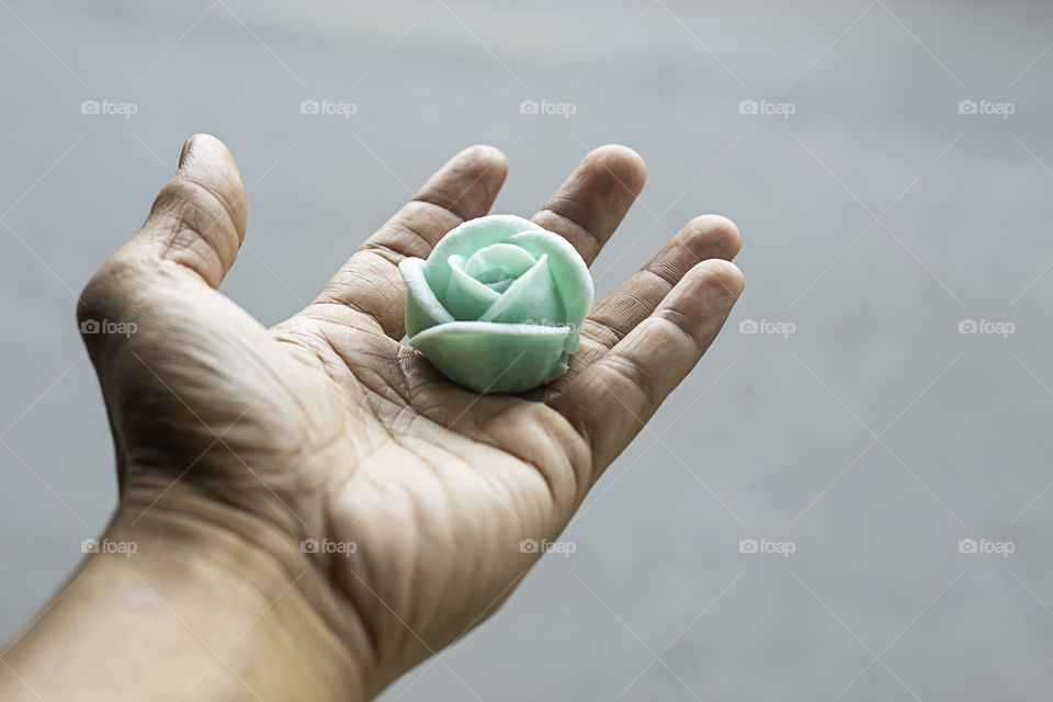 The hand holding the Thai dessert flower green or Aalaw candy.