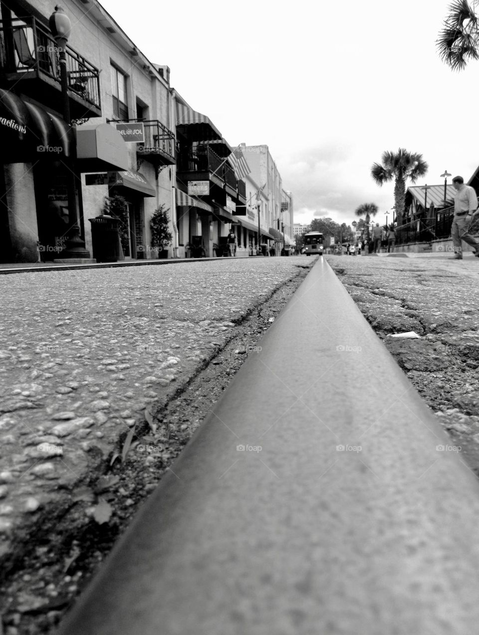 Taking a photo of a city street from the ground up - capturing all the elements of a black and white photo of a city street, a old train rail and an oncoming street car 