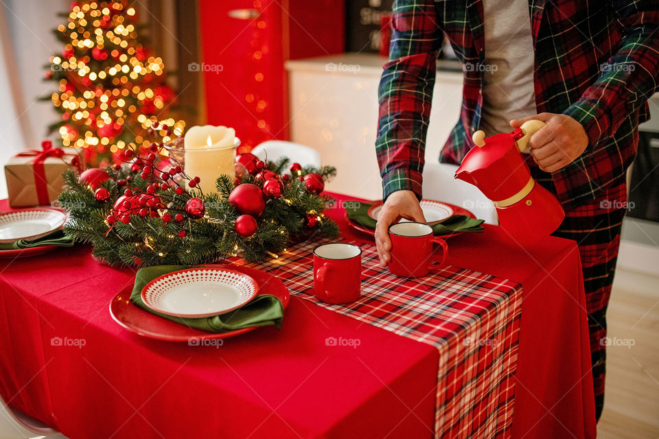 man sets a beautiful decorated winter table for a festive dinner.  Merry Christmas and Happy New Year.