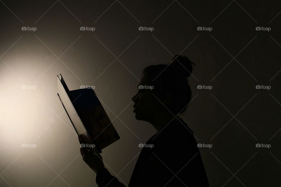 The shadow of a woman reading a book