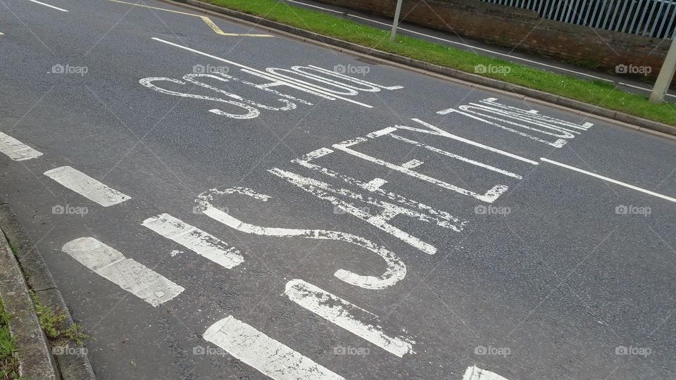 Road signs , painted road sign stating in English : school safety zone . 
road safety. road markings