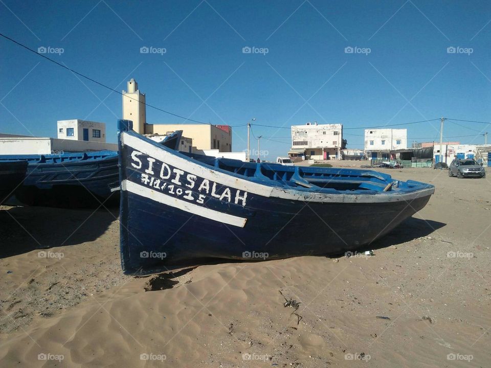 Beautiful village and blue boat on sand.