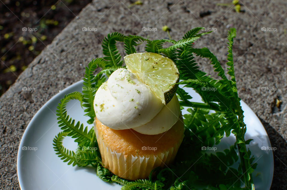 Lemon lime angel cake cupcake with creamy frosting outdoors on stone bench fresh summer treat conceptual background 