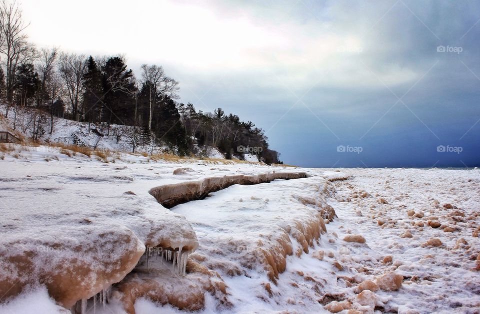 Snowy landscape against cloudy sky