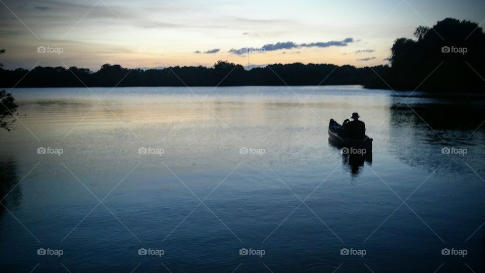 Man on lake in canoe at sunset