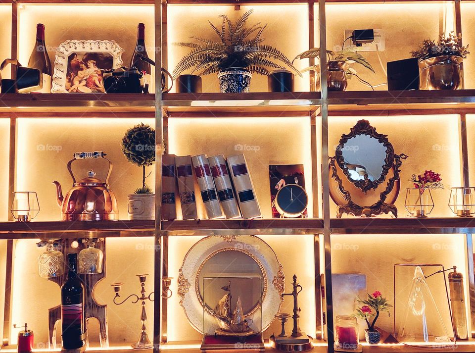 Decorative illuminated metal shelf with ornaments and souvenirs.  Dominance geometric shapes: triangle,  rectangle, and circles