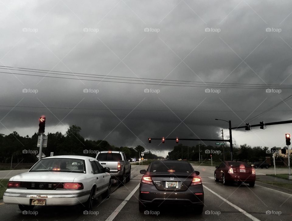 Storm clouds in distance with cars at stoplight in black and white