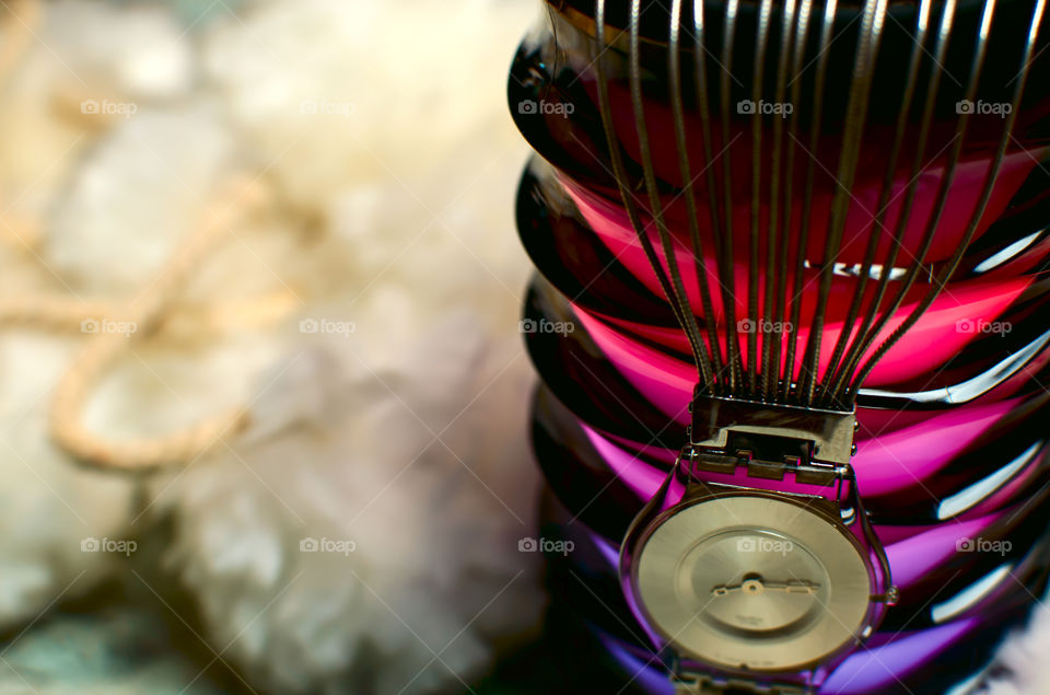 Retro swatch watch hanging from different color light and fluffy texture pompon background high angle view of bracelet selective focus with copy space  