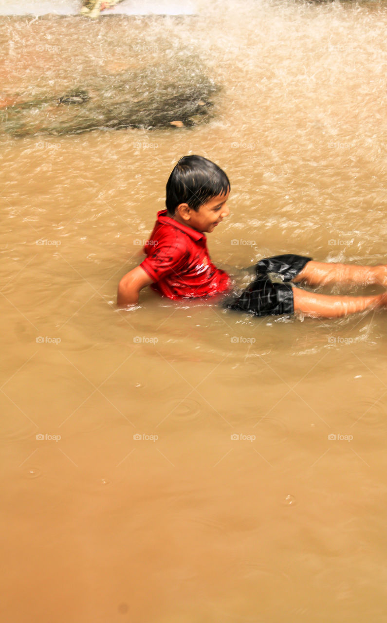 A kid enjoying in a heavy rainfall