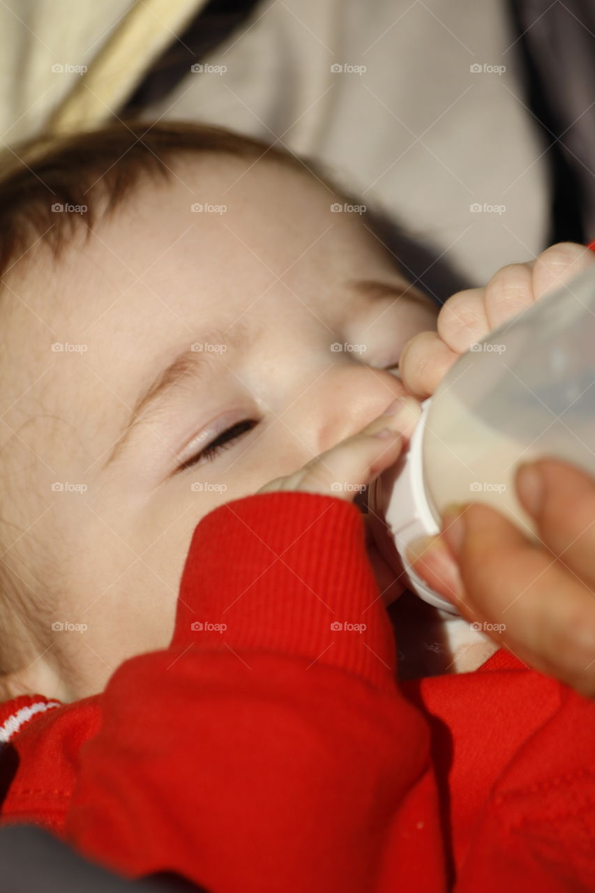 Close-up of a hand feeding milk to little boy