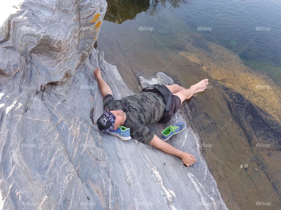 hombre descansando en piedra sobre el rio