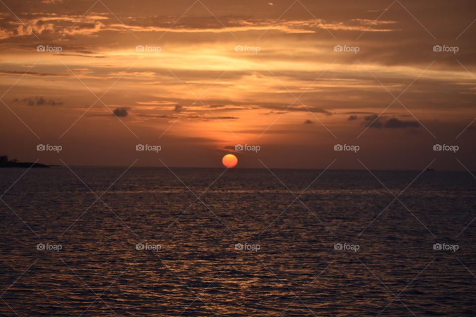 A beautiful sunset in the Carribean Island of Nassau. A landscaped picture of Yellow and orange sunset and sky over a rippling sea below.