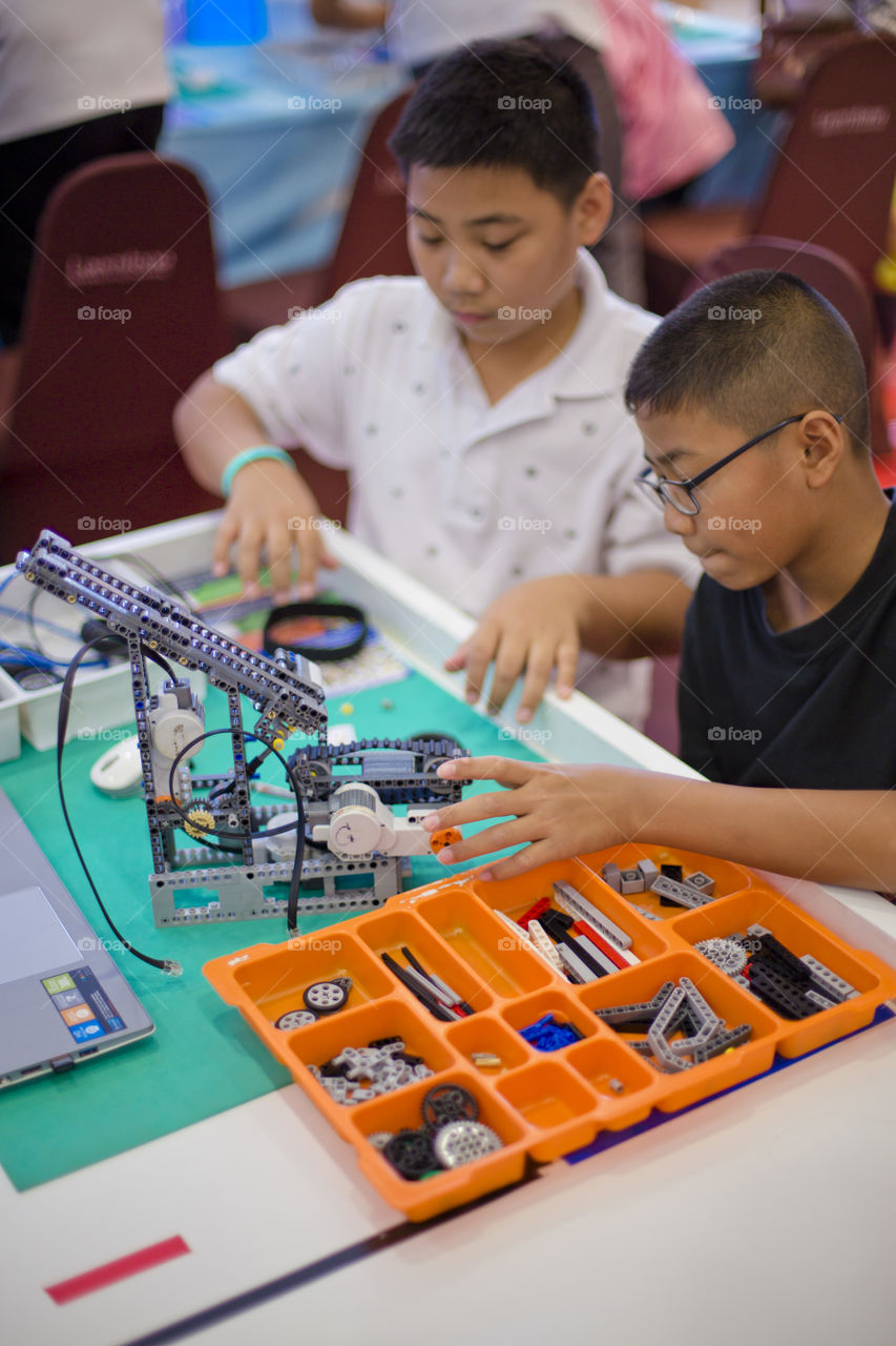 Smart Asian kids building robots. Making computerized robot with Lego