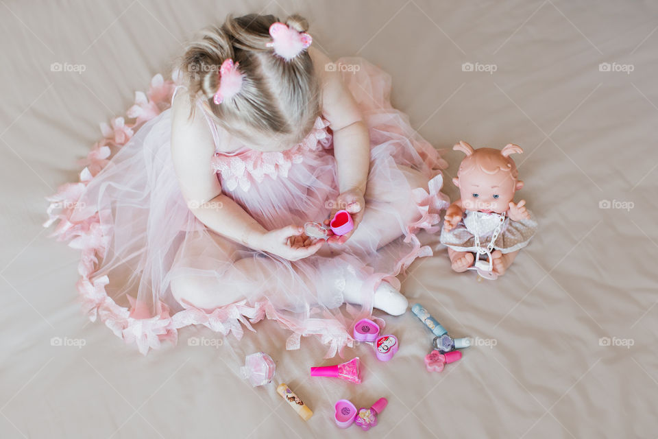 girl in a pink dress plays with a doll
