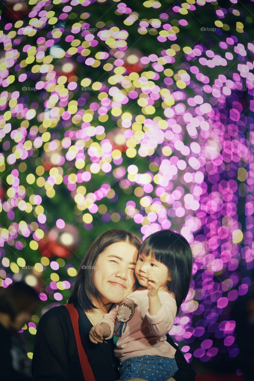Mother with her daughter against illuminated light