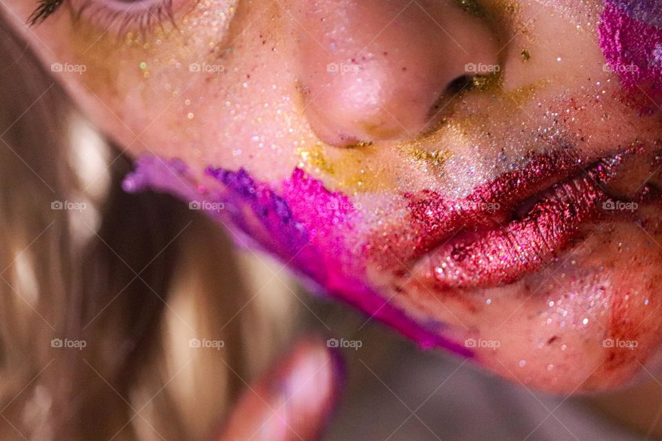 Child putting on a glitter make up on face