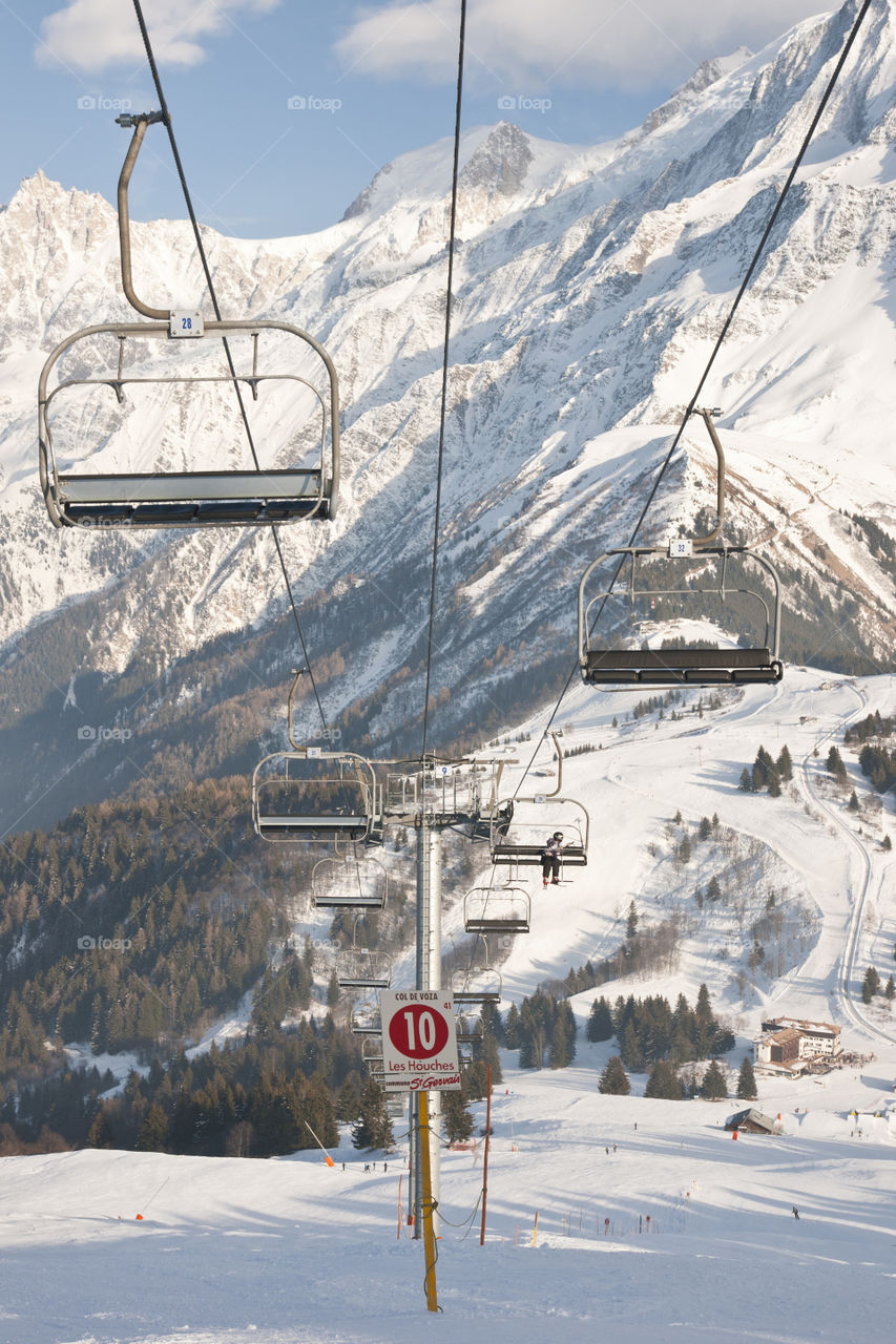 Four chair lifts on the Alps background.