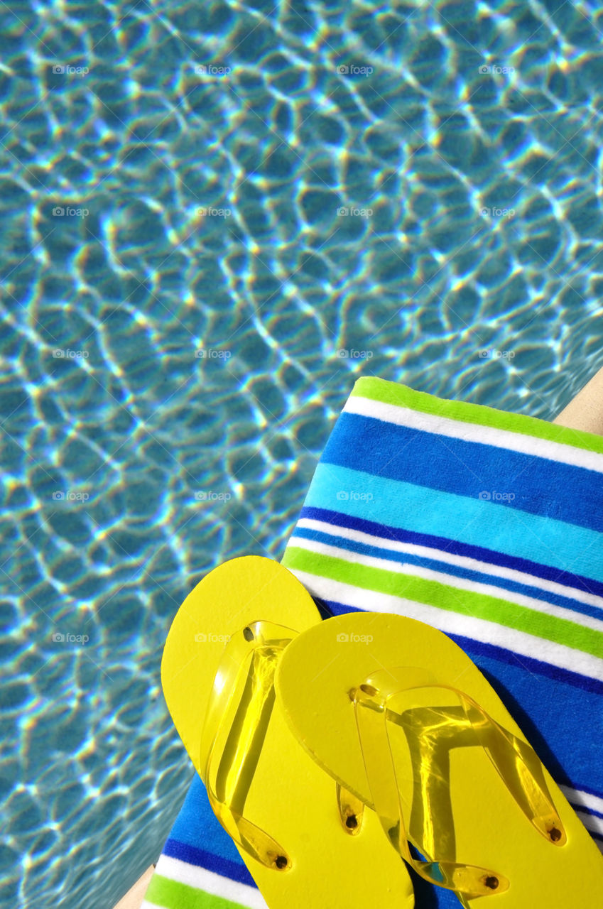 Flip-flops and beach towel sitting beside the swimming pool.
