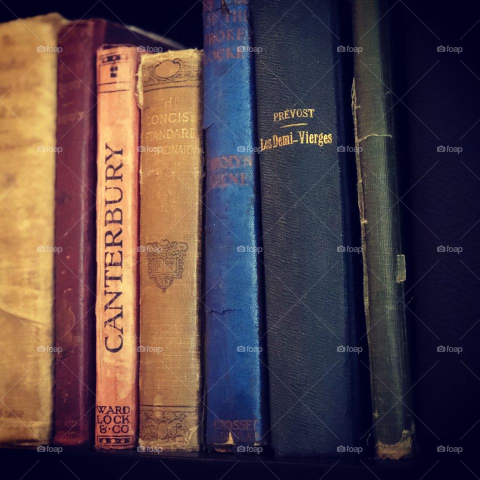Old worn cloth bound books on bookshelve