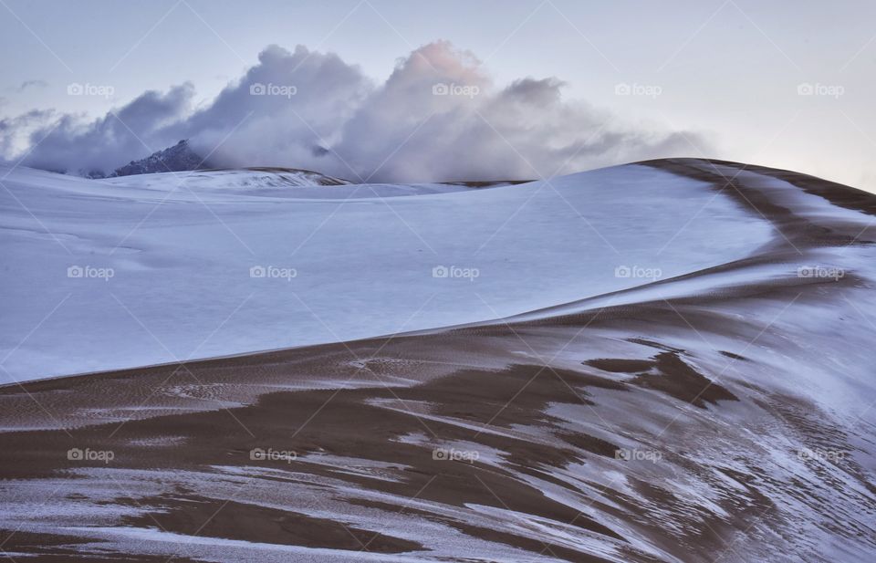 Great Sand Dunes National Park covered in snow. Very cloudy and moody shot with deep lighting. Clouds building and building.
