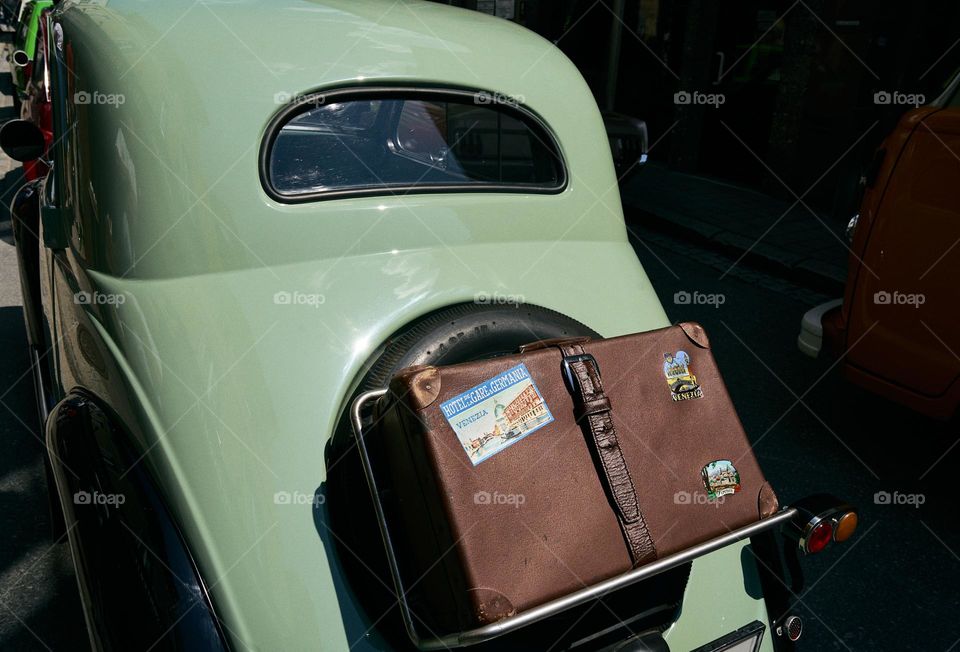 Vintage brown suitcase attached to the back of the oldtimer car