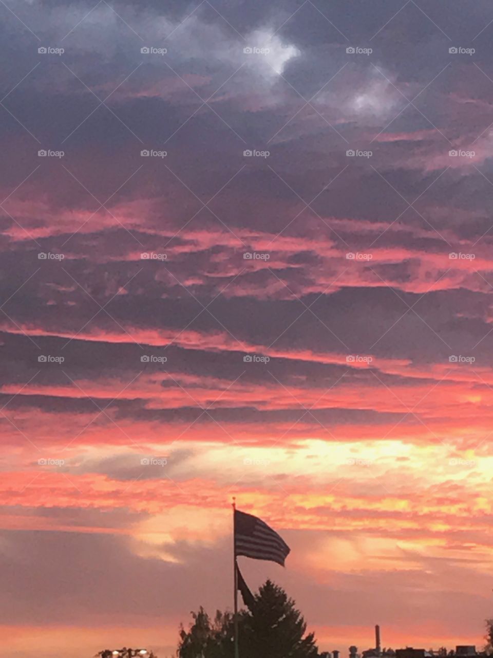 The American flag waves proudly before a majestic sunset, glorifying the beauty held within the United States of America. 