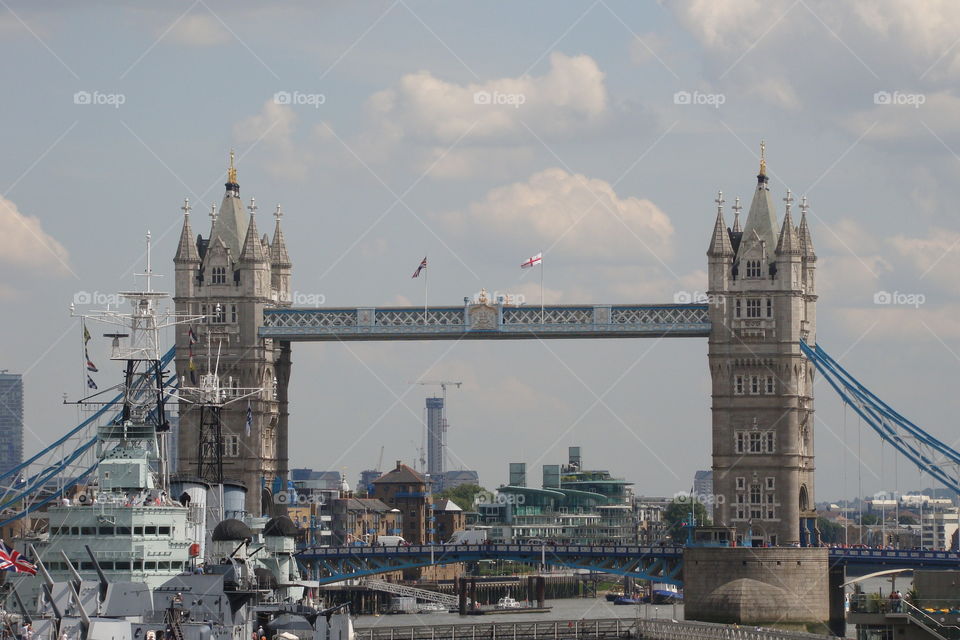 London tower bridge with ships in the river in front of it on a bright blue summer day.