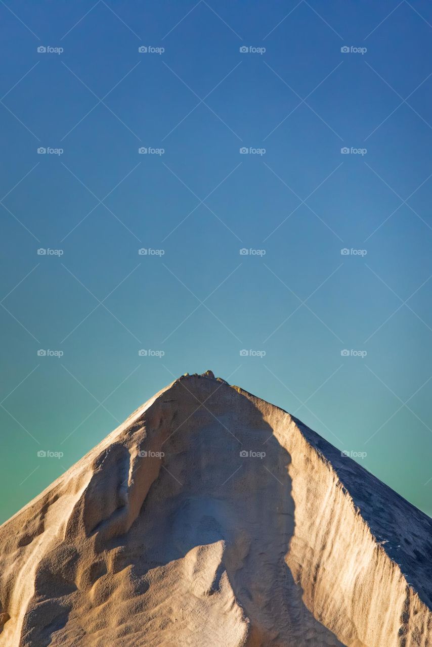 mountain of recycled sand against blue sky