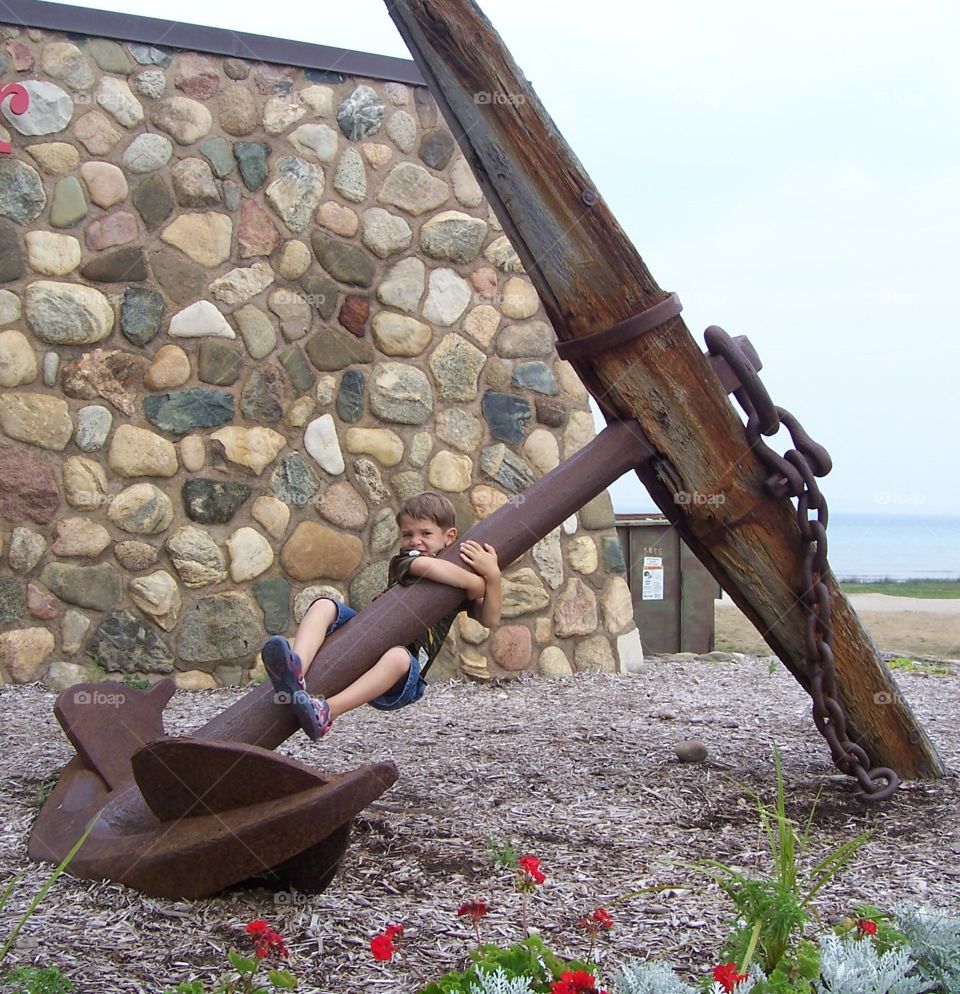 Boy hanging from large anchor
