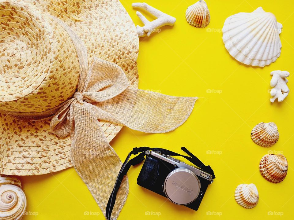 flat lay with summer hat, shells and camera