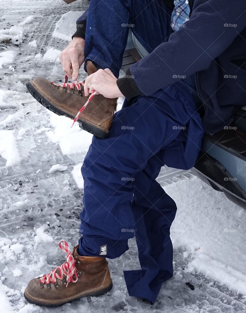 Pulling on boots off the back of a car to go play in the snow. 