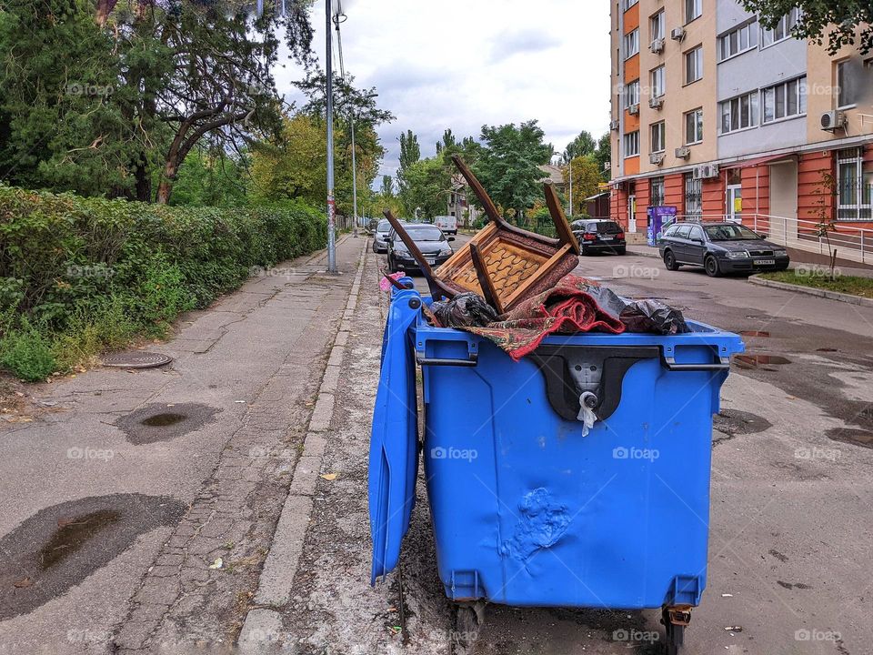 old chair thrown into the trash can