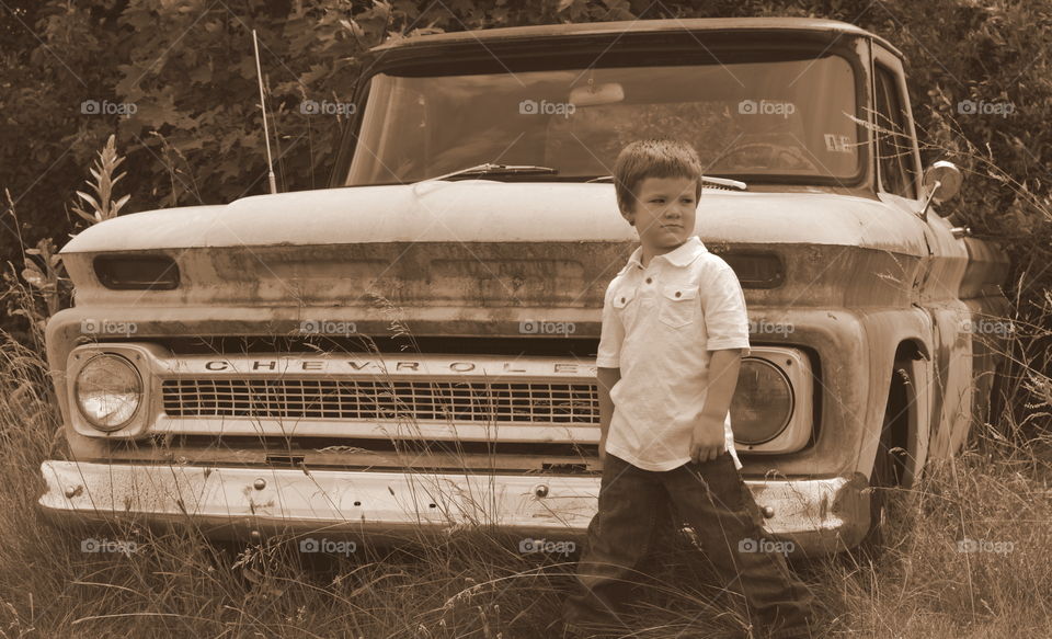 Little boy standing against vintage car