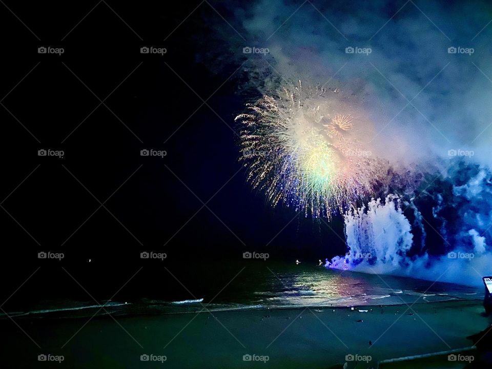 Fireworks exploding over the ocean creating beautiful displays of light during the night