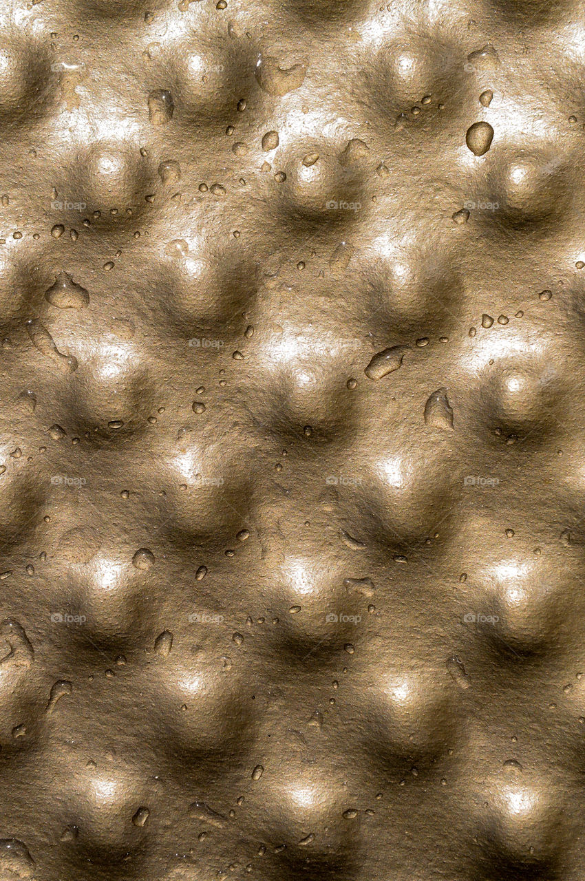 Copper colored bumpy texture with drops of water