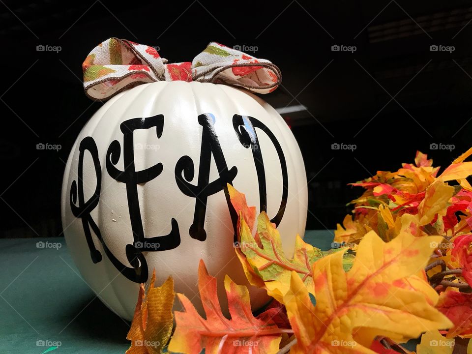 Pumpkin with fake fall leaves and the word read on it 