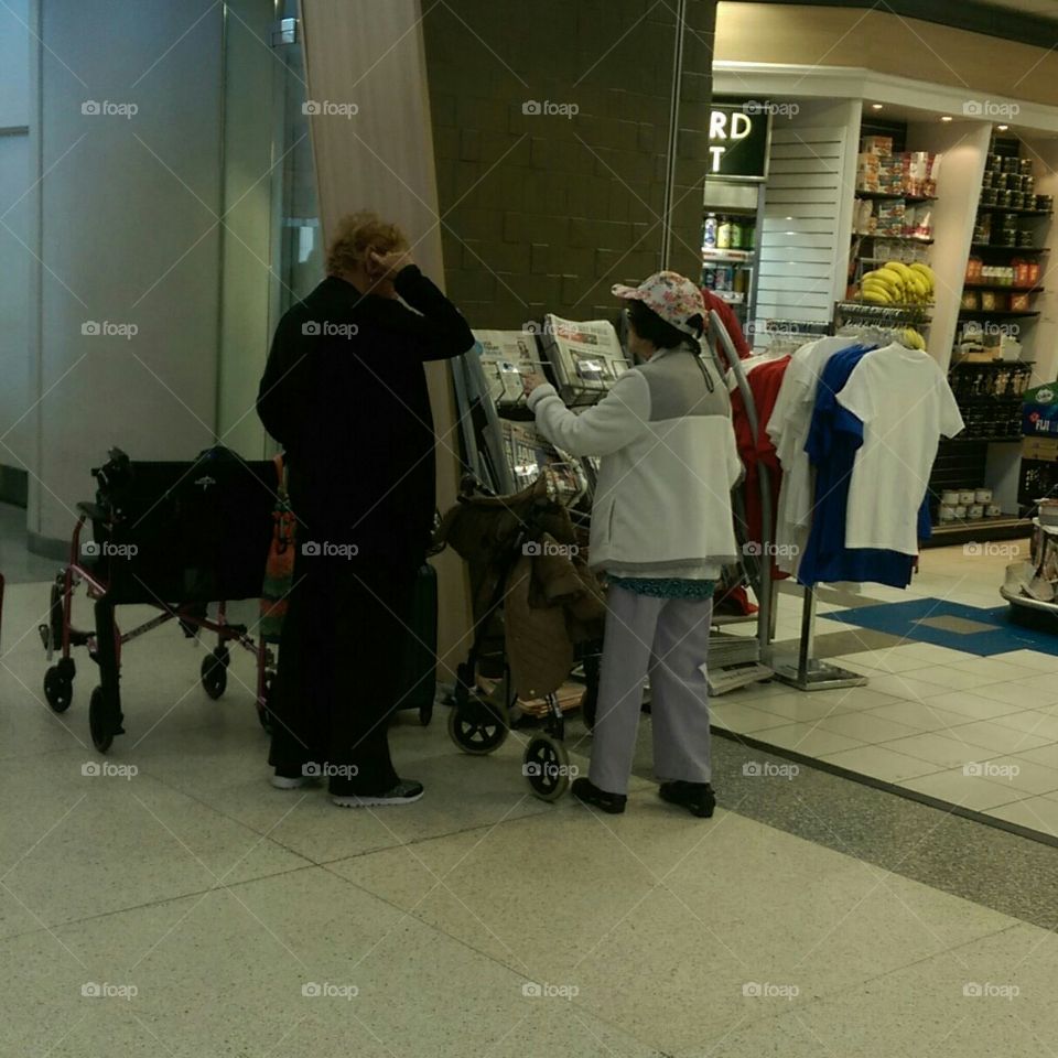 Two elderly women converse in an airport