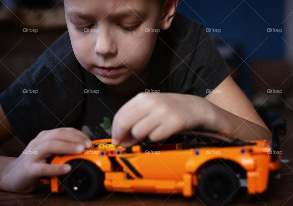 A boy assembles a race car model constructor