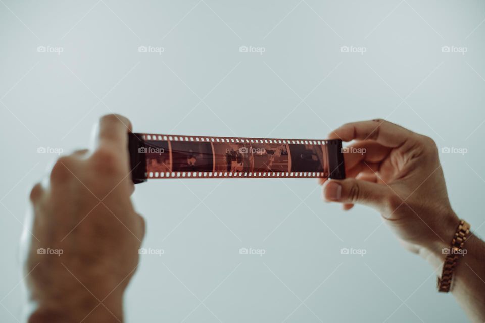 Adult hand holding a camera film on white background