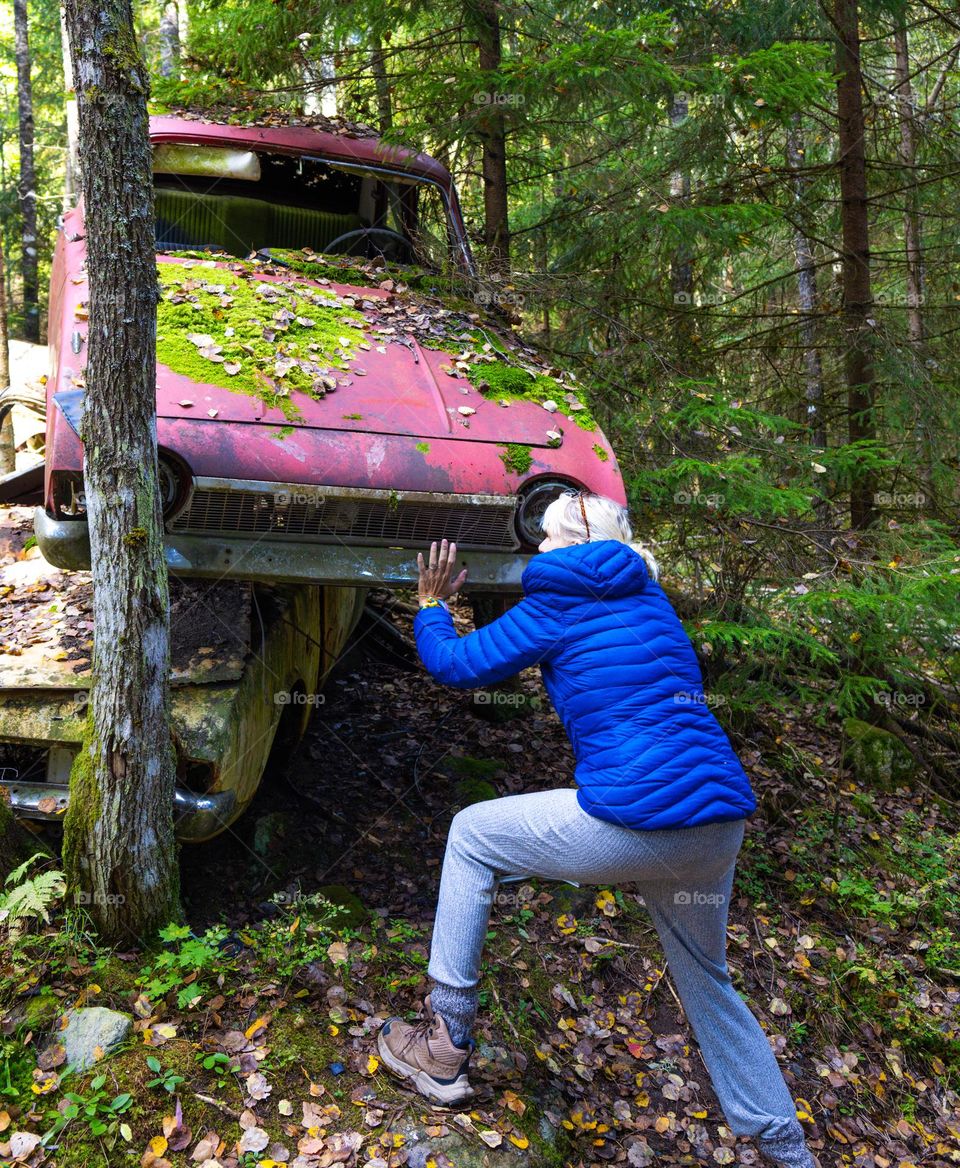 Fall time in the forest . I old broken car and a woman. Action time. Carry and push . clear air