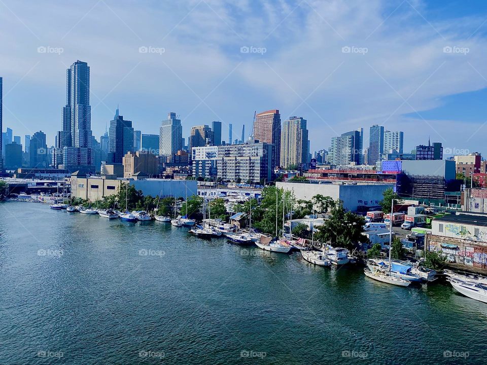 This is „Newtown Creek“ seen from the top of the „Pulaski Bridge“ on a hot sunny summertime afternoon. Various types of boats are lined up and tied to the shore here which adds to the special appeal of this locale. 2023. Hypnotic Productions