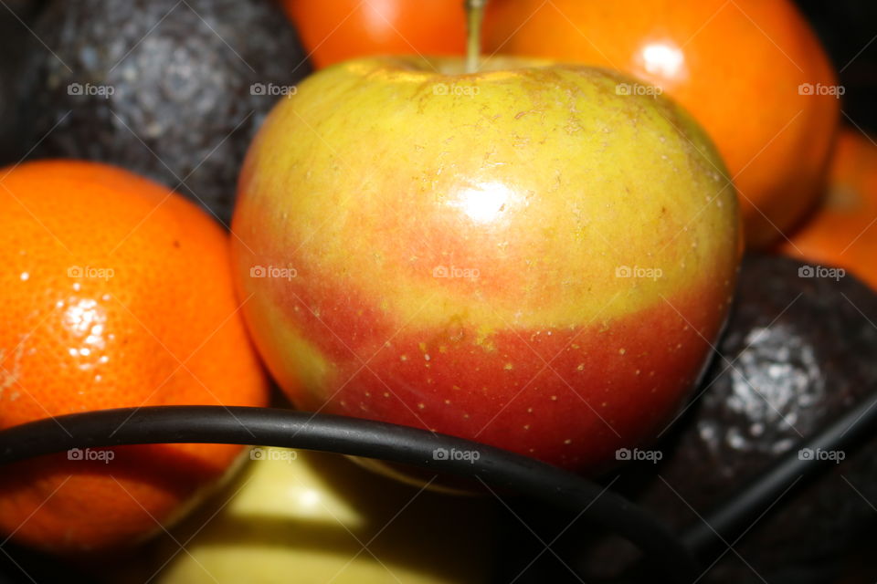 A bowl of fruits including apples, mandarin and avocados
