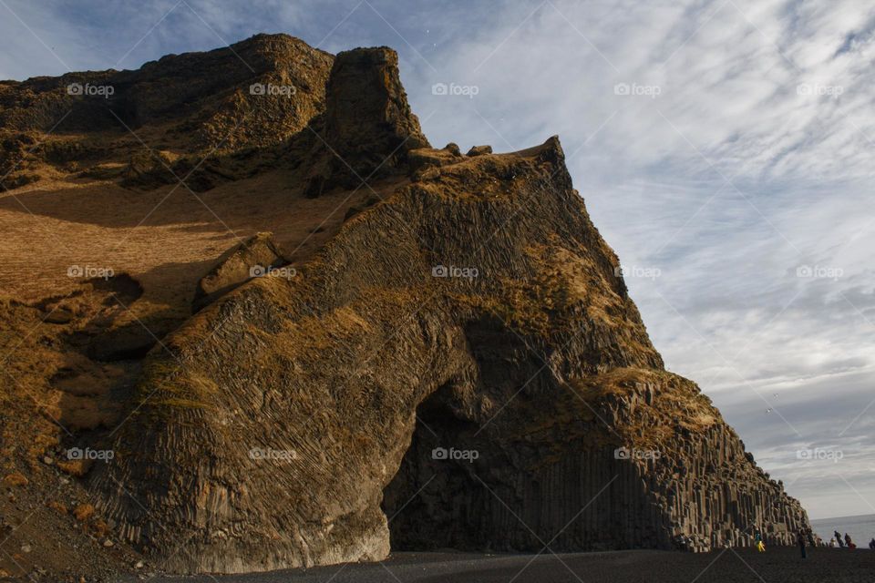 Tall versus small - rock in Iceland with ant-like people next to it