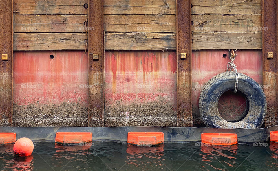 Tire hanging on the side of an industrial barge working on a canal