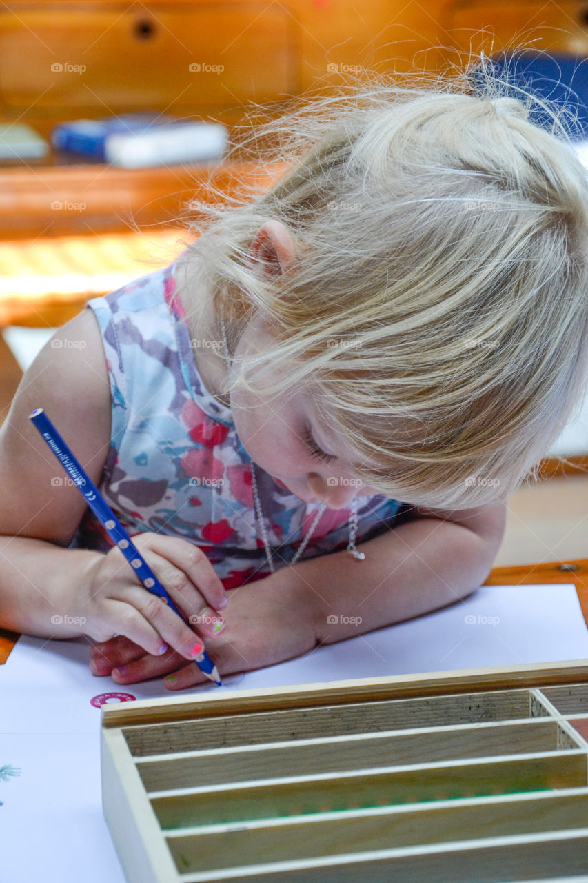 Young girl of two years old is painting on paper.