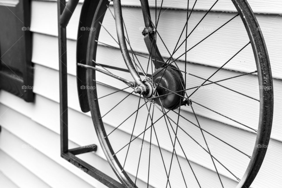 Close-up black and white minimalist image of a bicycle tire hung on outdoor siding